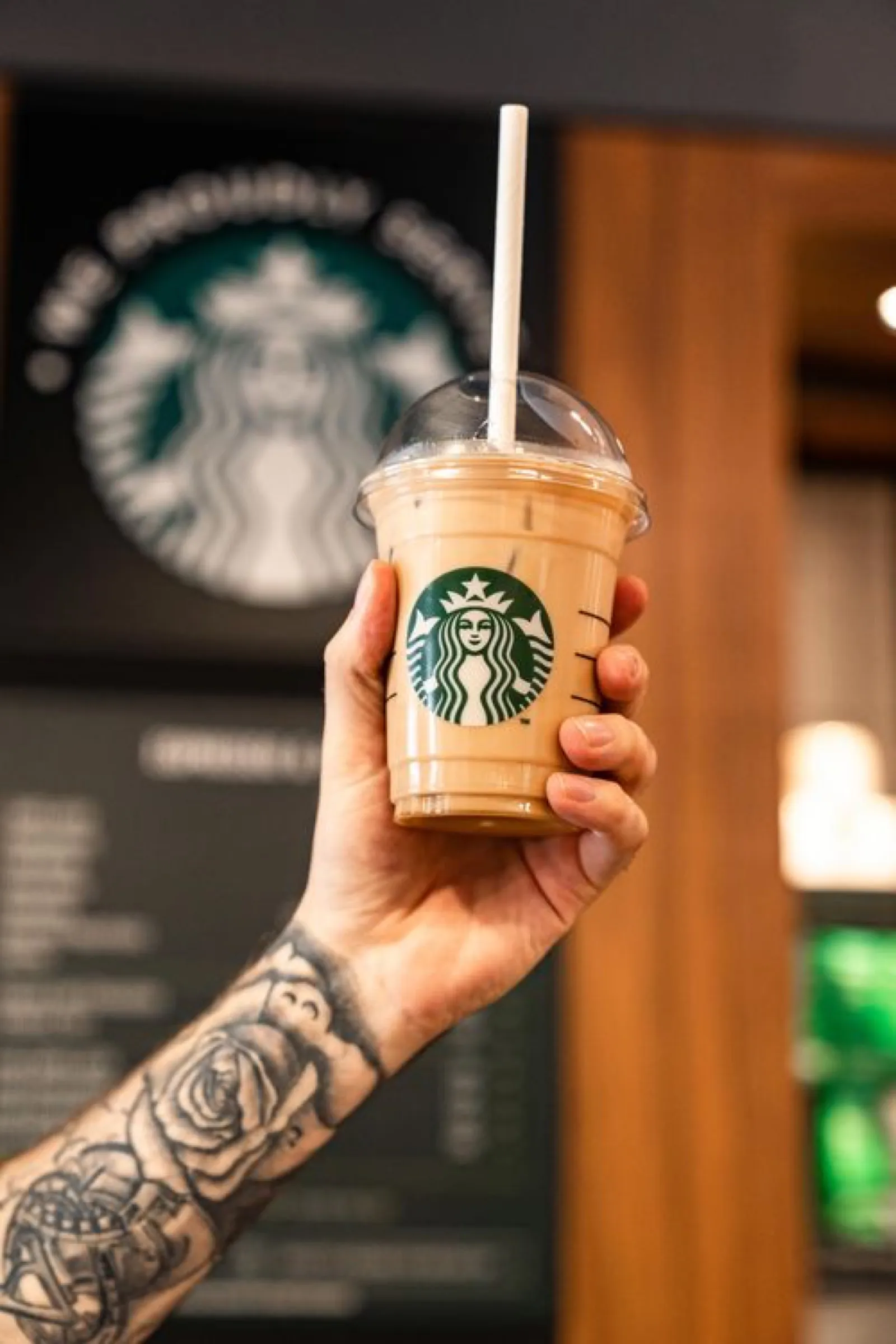 A hand holding a Starbucks cup