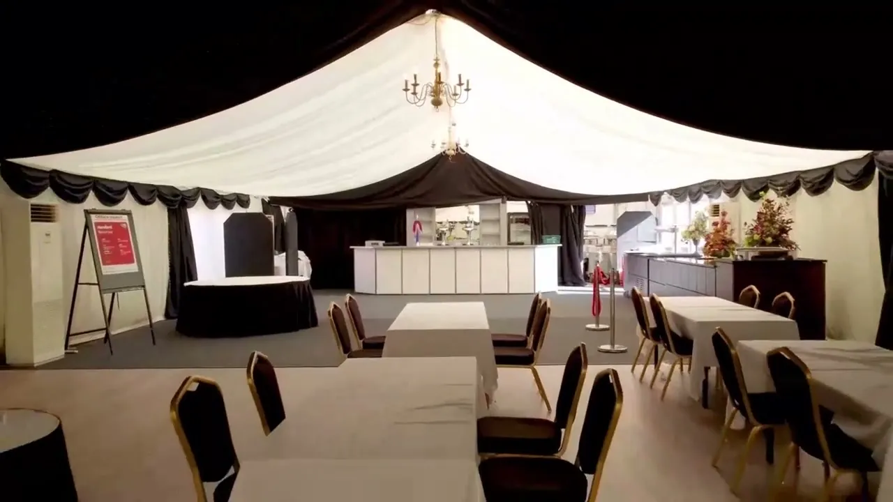 Grand Marquee interior with white drapes, chandeliers and long tables